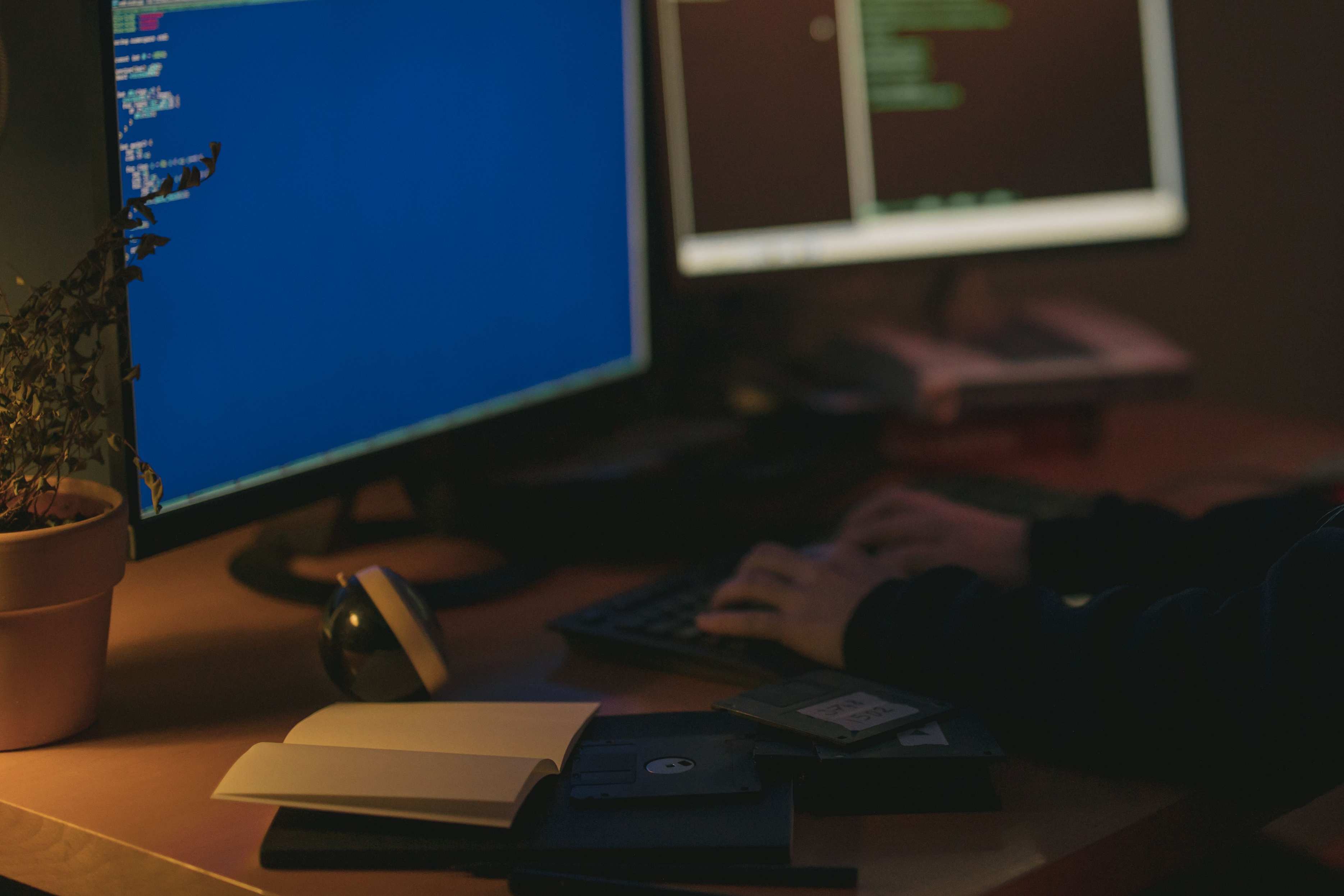 Computer screen showing source code during a late review session, programming in a dimly lit room with dual monitors